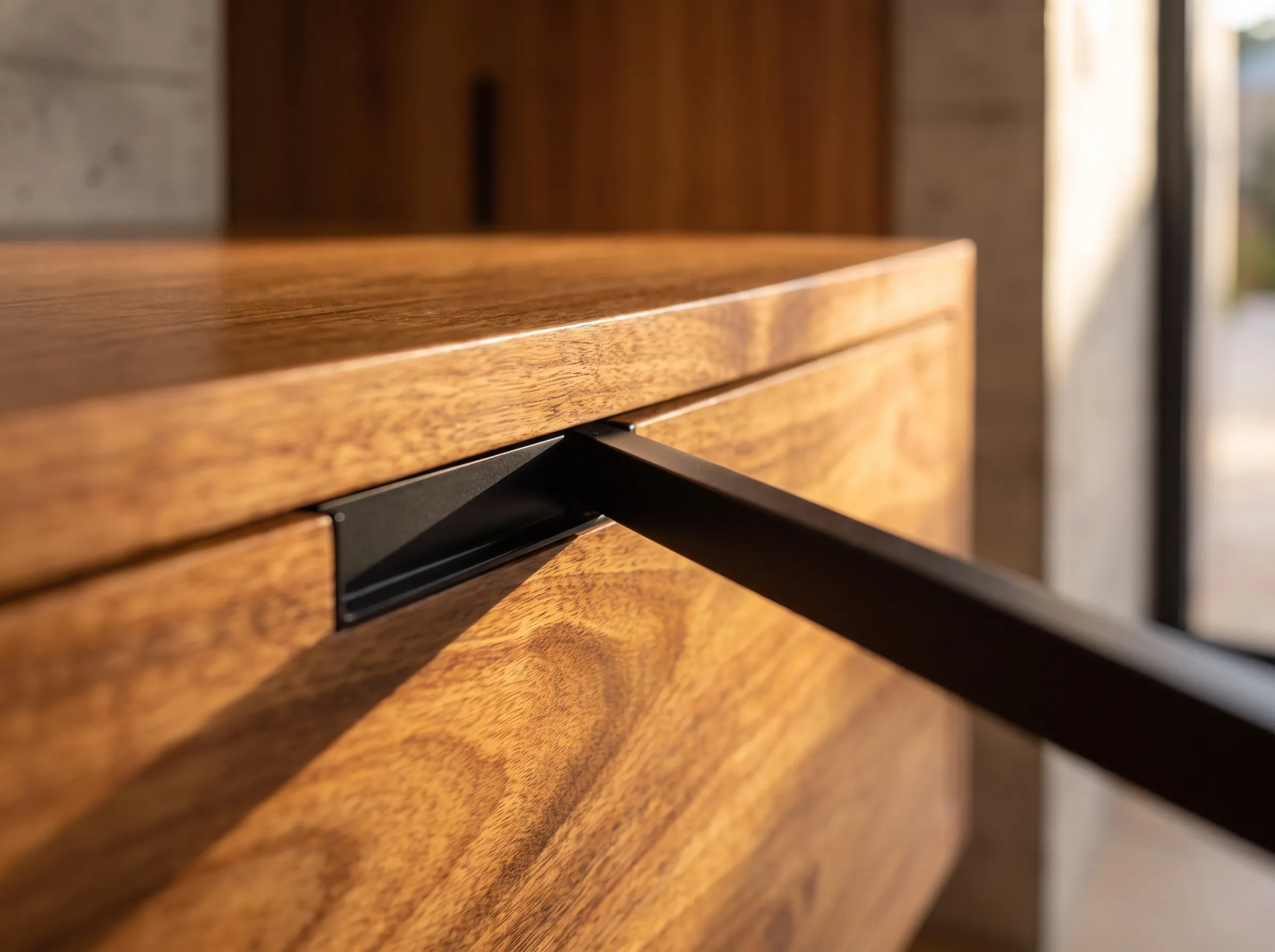 Detail crop: spotted-gum drawer front with recessed black pull and crisp shadow line