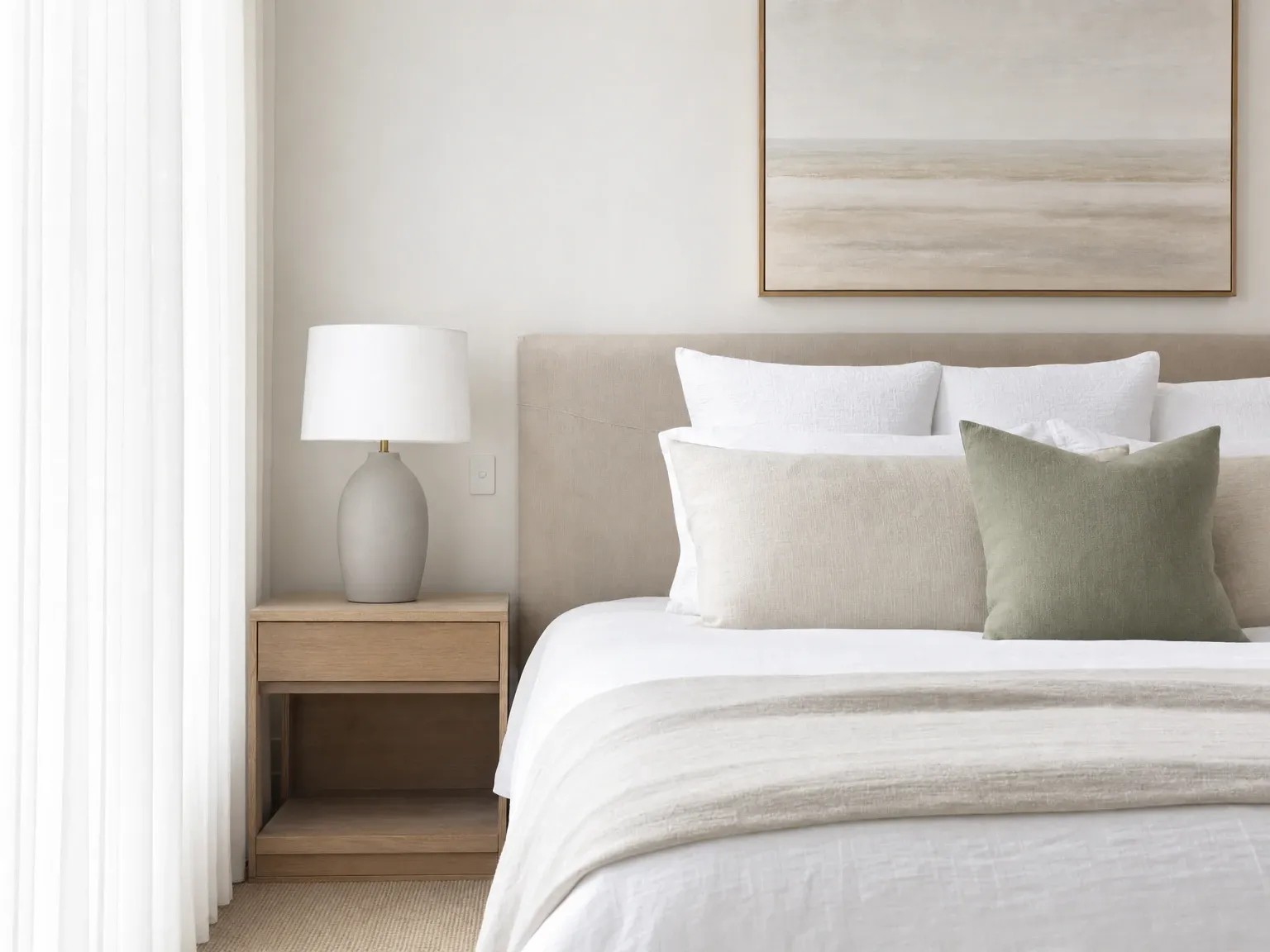 The same Australian bedroom with a made bed and bedside table cleared except for a lamp and one styled item