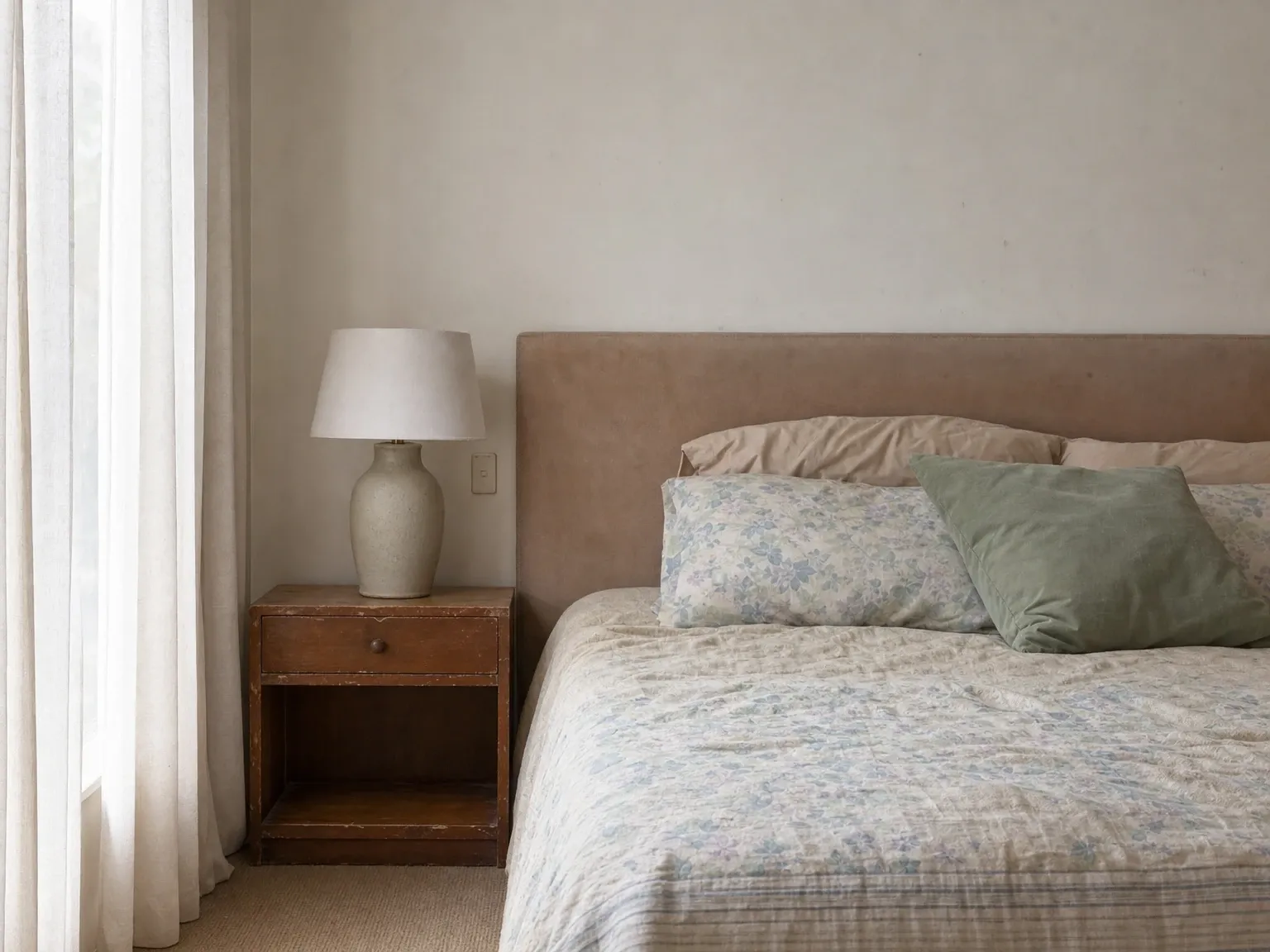 Australian master bedroom with cluttered bedside table showing phone charger, personal items and an unmade bed