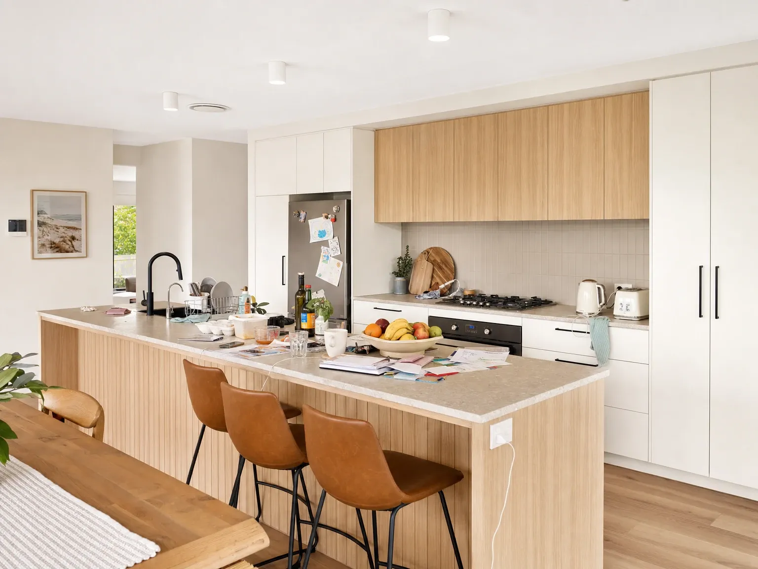 Australian kitchen with a cluttered island bench showing a kettle, appliance cords, mugs and everyday items