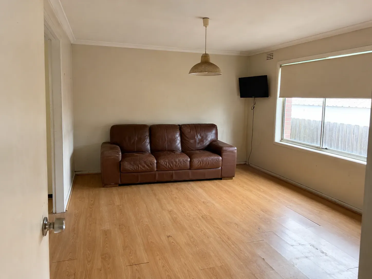 Lived-in Australian living room during early renovation planning with dated finishes and minimal styling