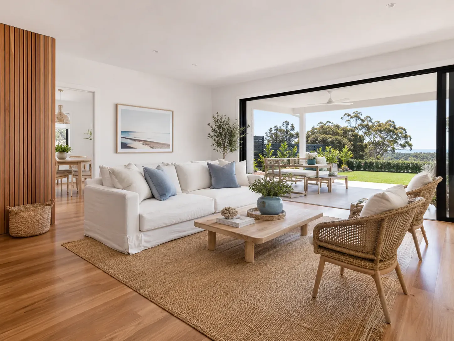 Relaxed Australian modern-coastal living room with white walls, light timber floors, linen sofa and open sliding doors to a covered patio