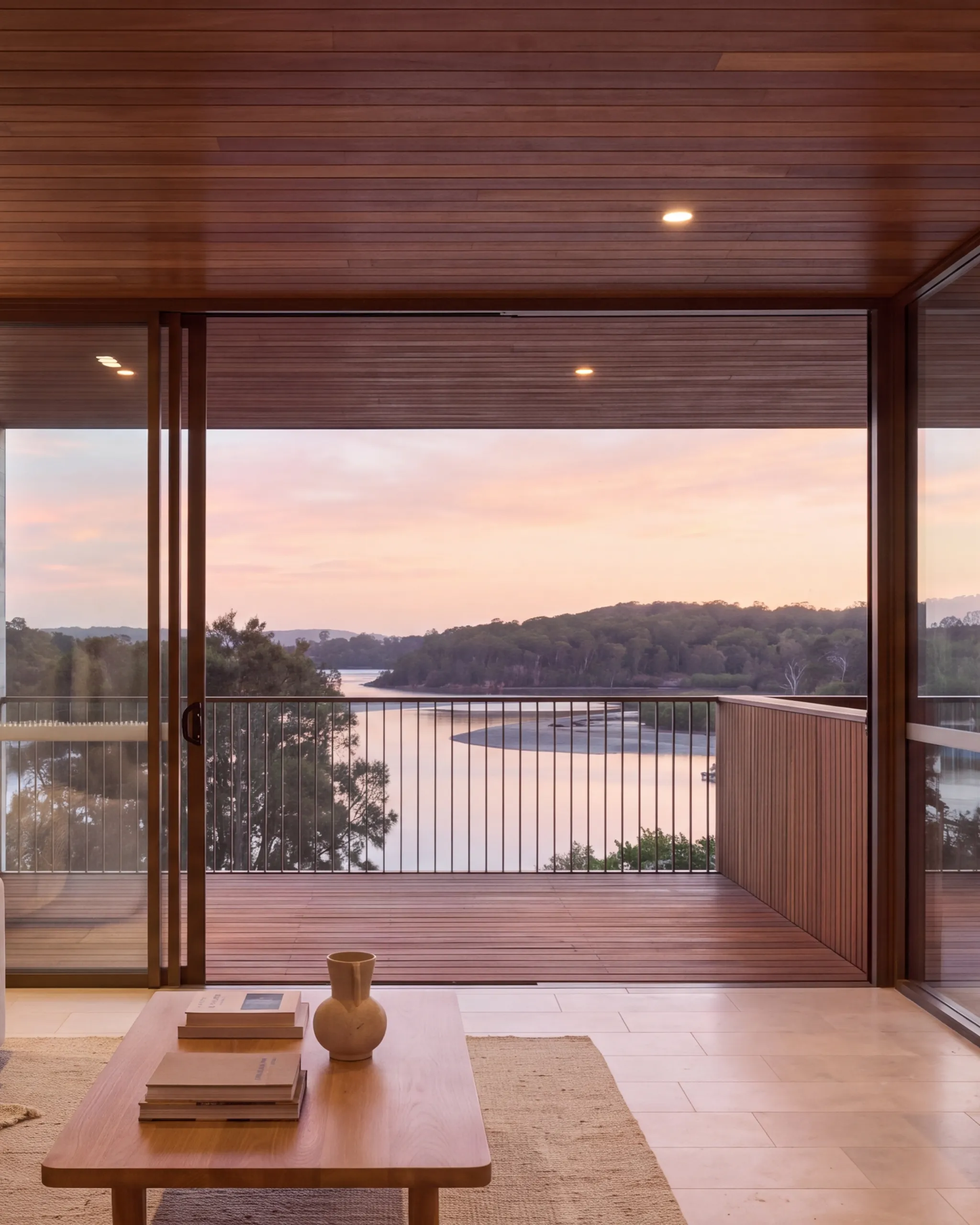 Carousel tile two: the living room opening onto the balcony, the creek and headland at dusk