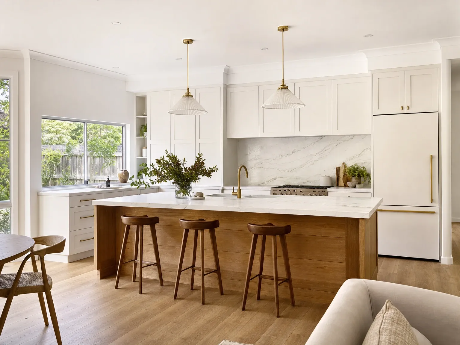 The same kitchen restyled with warm white cabinetry, timber accents and veined stone